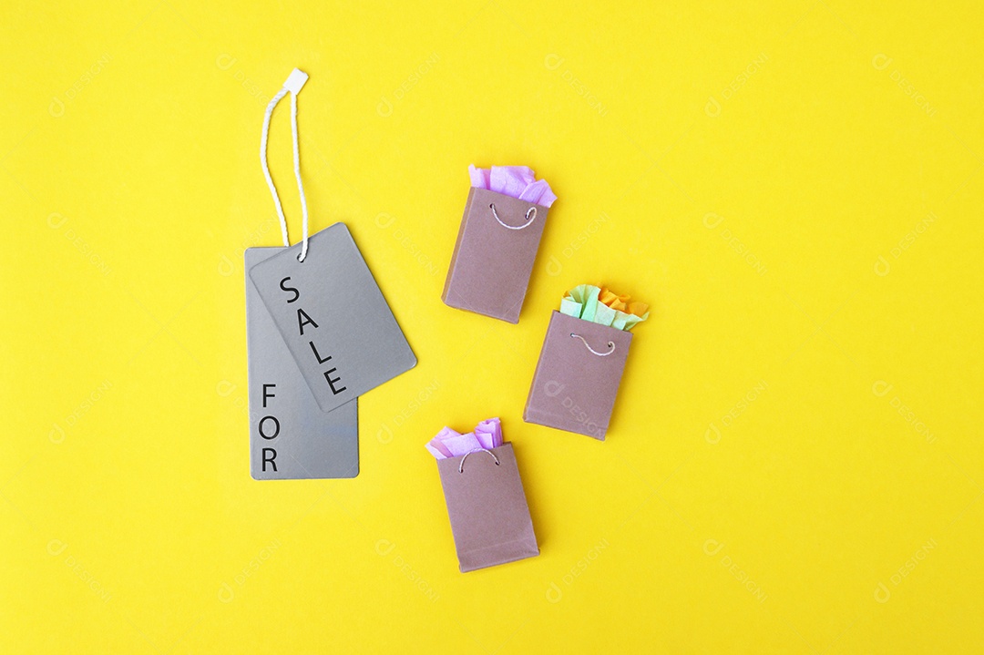 Sacolas kraft e etiquetas escrito á venda sobre fundo amarelo