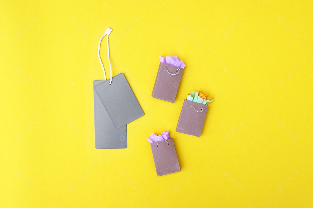 Etiquetas cinza e sacolas de compras sobre fundo amarelo