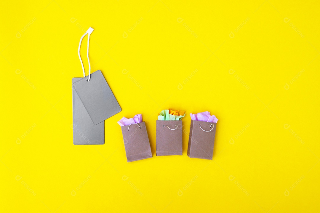 Etiquetas cinza e sacolas de compras sobre fundo amarelo