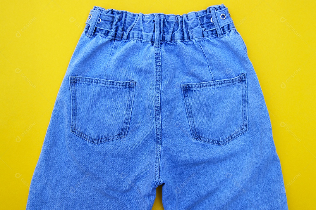 Detalhes de uma roupa jeans parte de trás sobre fundo amarelo