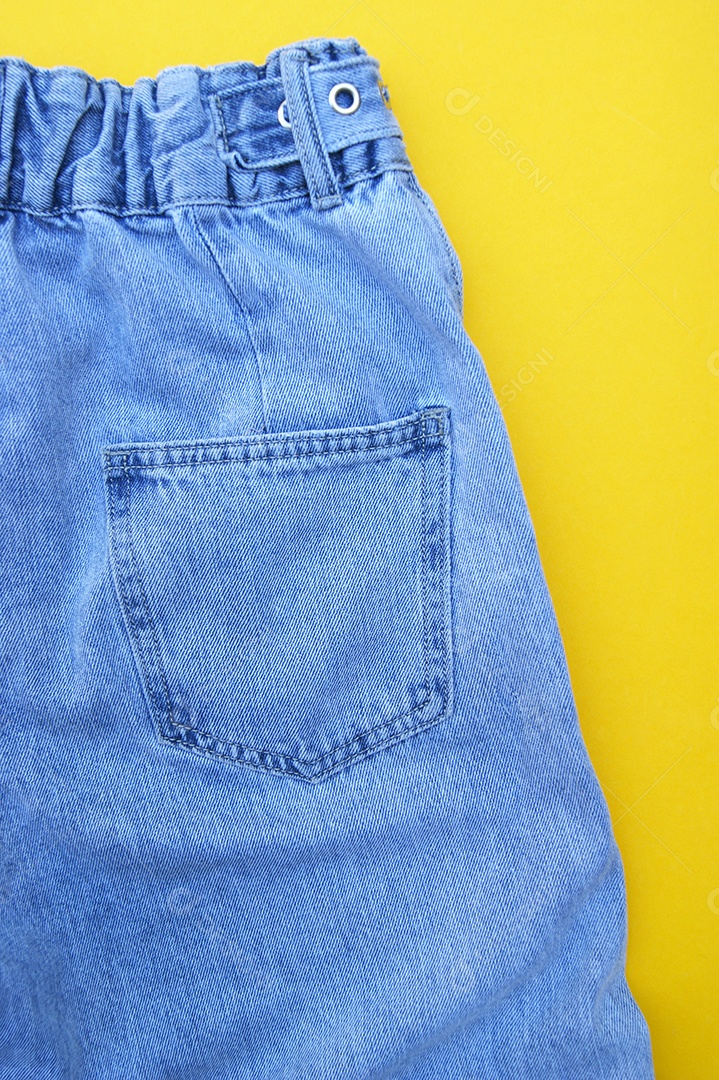 Detalhe de uma roupa jeans sobre fundo amarelo
