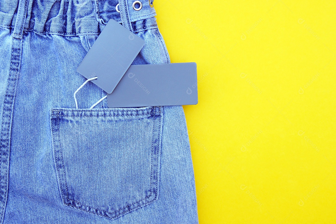 Jeans com etiquetas cinzas conceito de compras sobre fundo amarelo