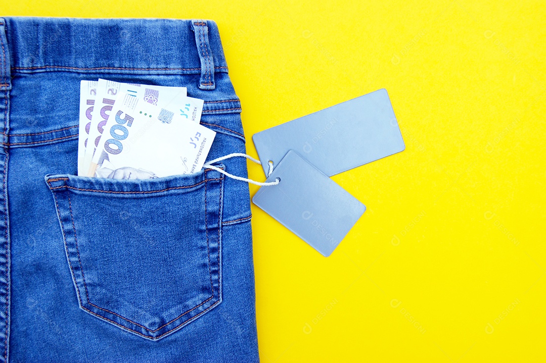 Jeans azul bonito etiquetados a venda com dinheiro hryvnia no bolso em fundo amarelo