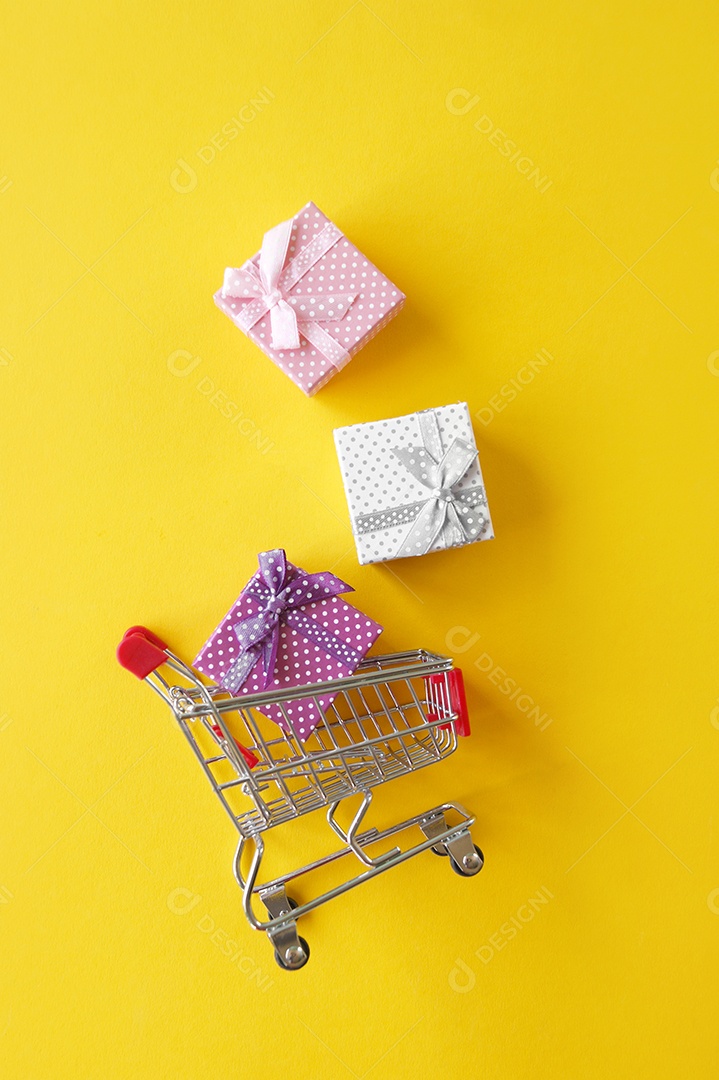Carrinho de compra com presentes dentro sobre fundo amarelo