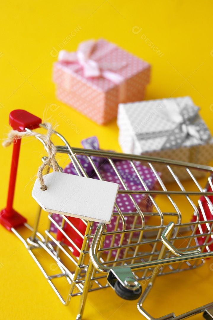 Carrinho de compra com presentes dentro sobre fundo amarelo
