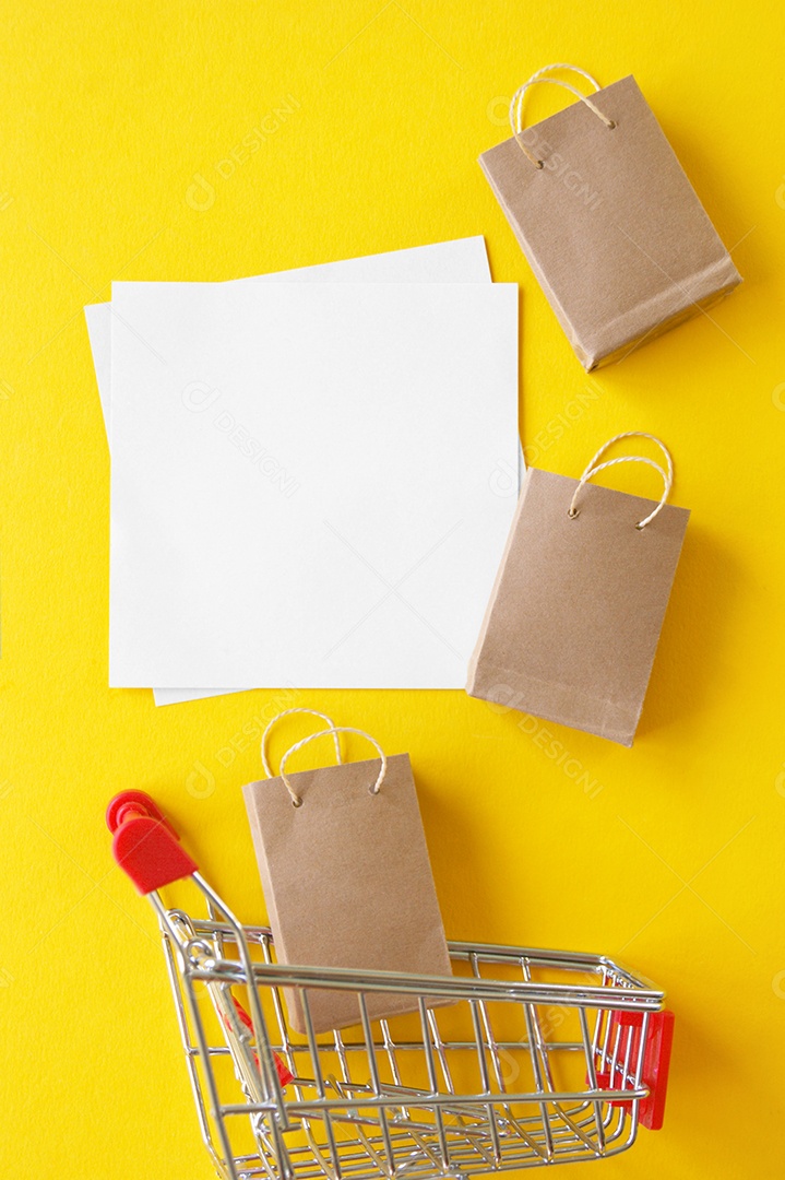 Carrinho com sacolas kraft e papéis sobre undo amarelo