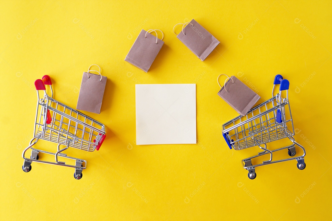 Mini carrinho de compra sacolas kraft e papel sobre fundo amarelo