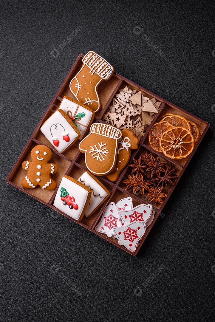 Lindos biscoitos de gengibre de Natal de cores diferentes em uma placa de cerâmica sobre uma mesa de concreto escuro