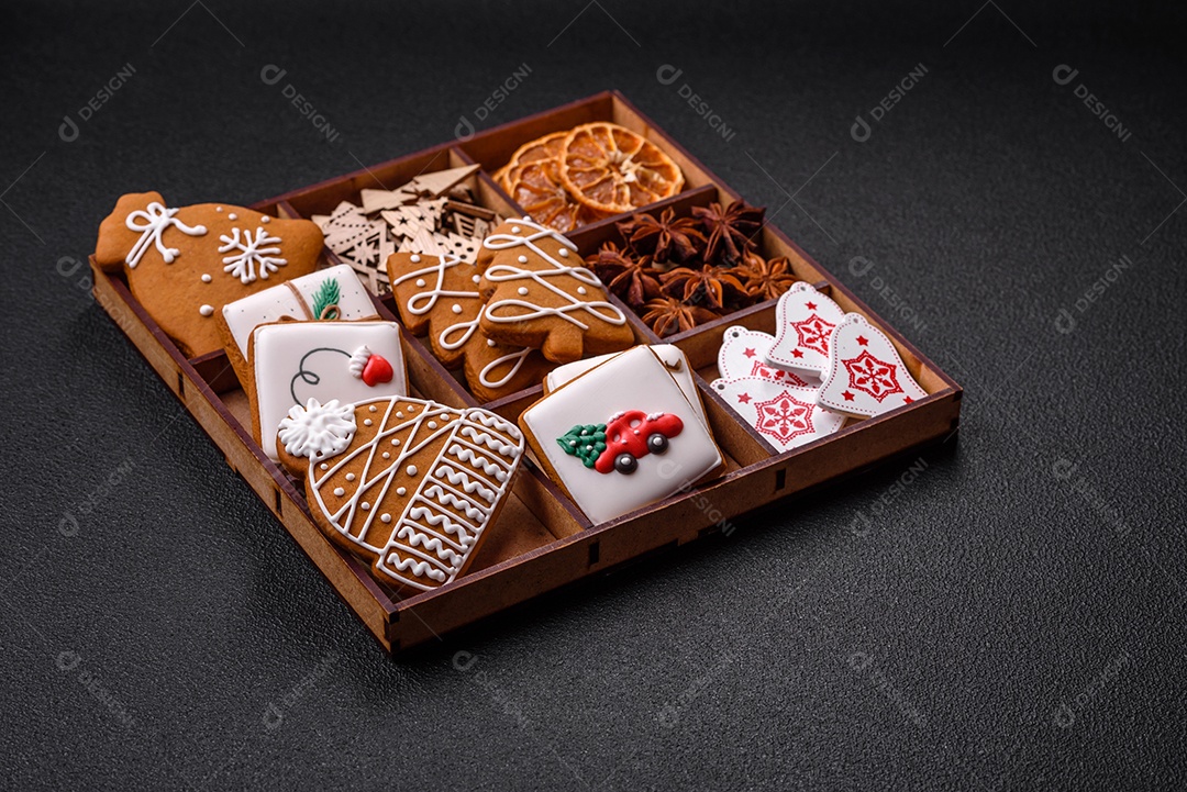 Lindos biscoitos de gengibre de Natal de cores diferentes em uma placa de cerâmica sobre uma mesa de concreto escuro