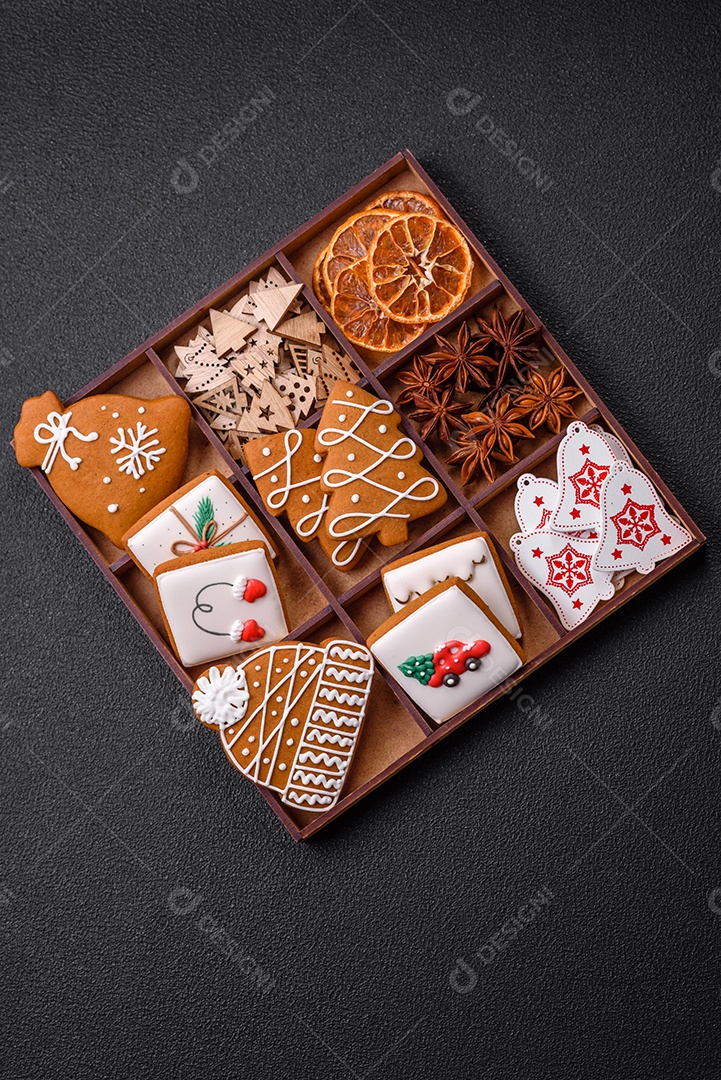 Lindos biscoitos de gengibre de Natal de cores diferentes em uma placa de cerâmica sobre uma mesa de concreto escuro