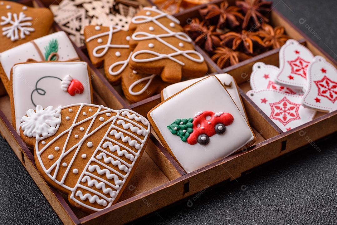 Lindos biscoitos de gengibre de Natal de cores diferentes em uma placa de cerâmica sobre uma mesa de concreto escuro