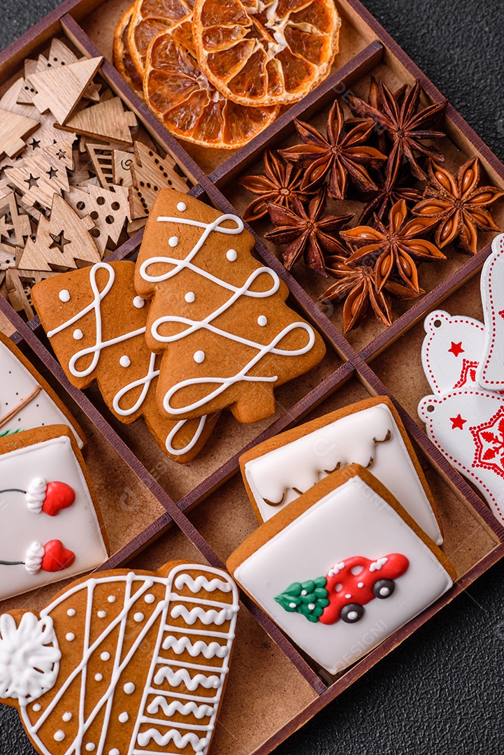 Lindos biscoitos de gengibre de Natal de cores diferentes em uma placa de cerâmica sobre uma mesa de concreto escuro