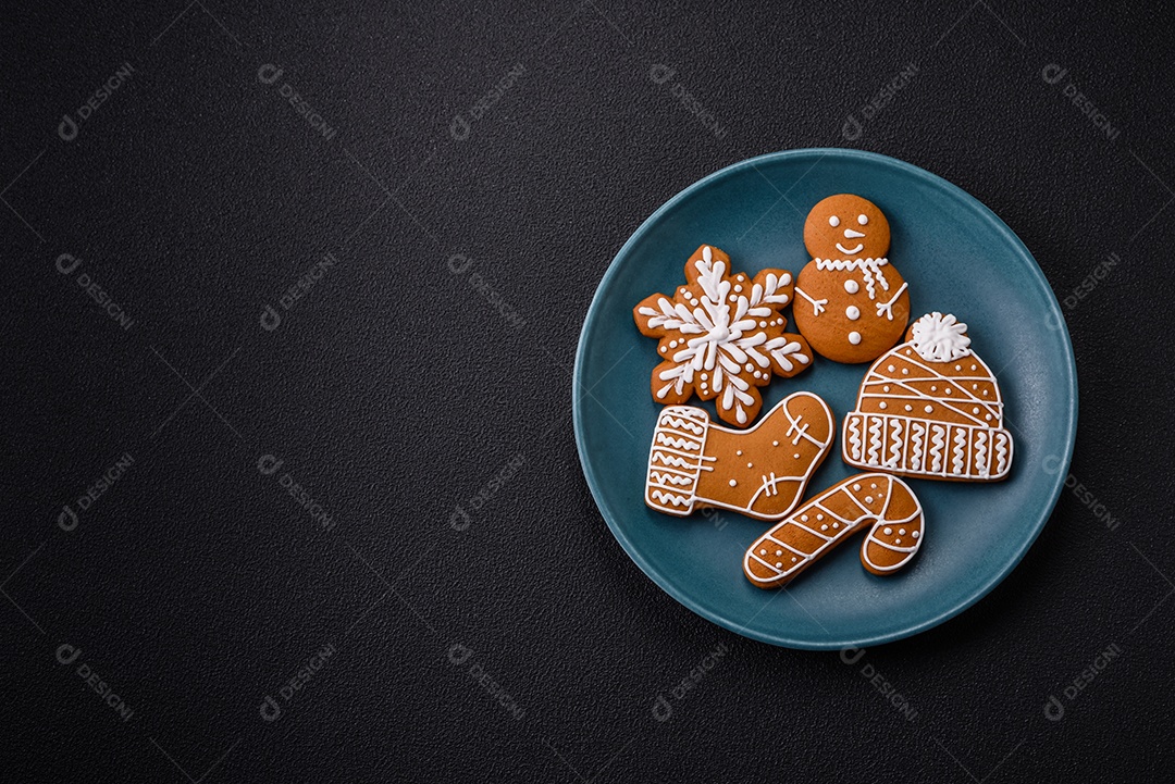 Lindos biscoitos de gengibre de Natal de cores diferentes em uma placa de cerâmica sobre uma mesa de concreto escuro