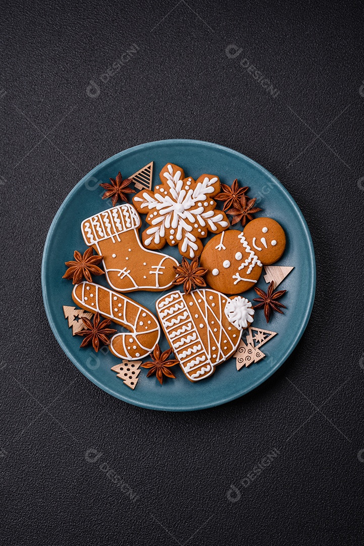 Lindos biscoitos de gengibre de Natal de cores diferentes em uma placa de cerâmica sobre uma mesa de concreto escuro