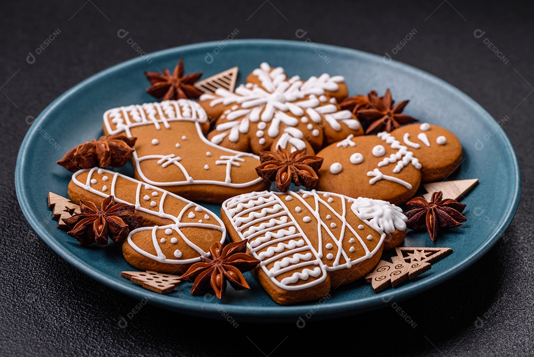 Lindos biscoitos de gengibre de Natal de cores diferentes em uma placa de cerâmica sobre uma mesa de concreto escuro