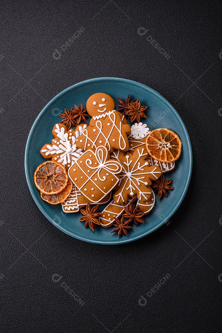 Lindos biscoitos de gengibre de Natal de cores diferentes em uma placa de cerâmica sobre uma mesa de concreto escuro