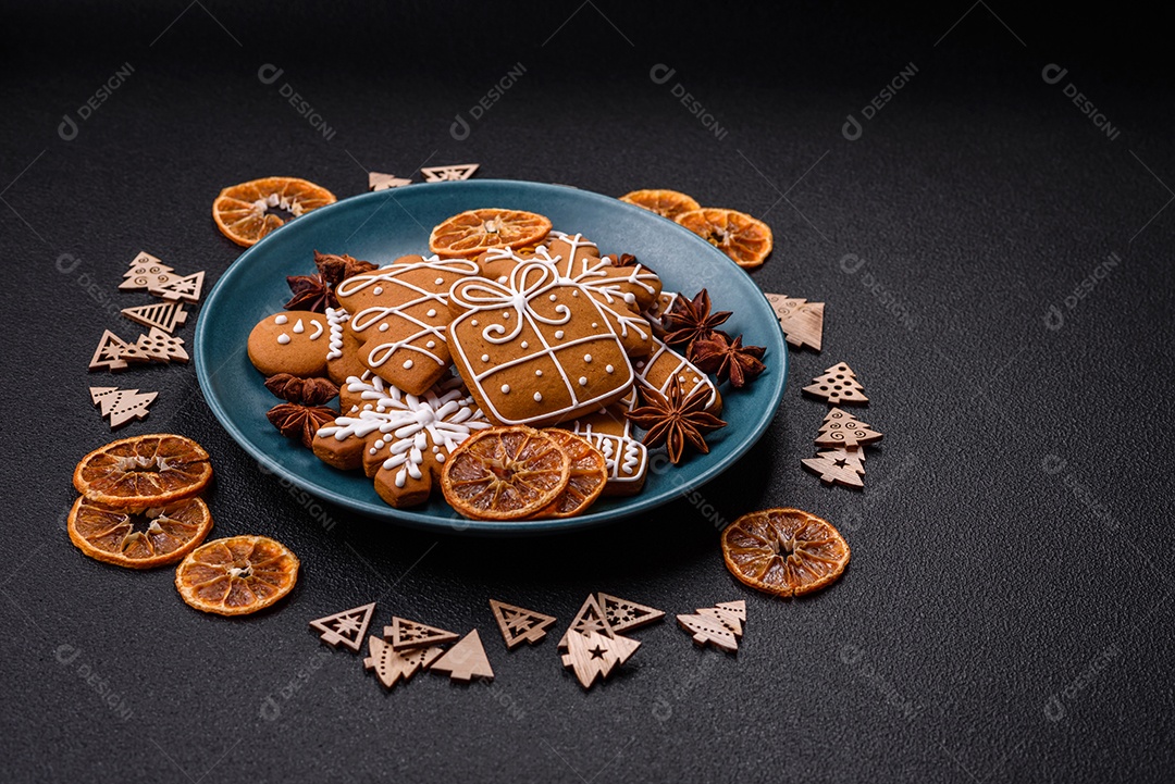 Lindos biscoitos de gengibre de Natal de cores diferentes em uma placa de cerâmica sobre uma mesa de concreto escuro