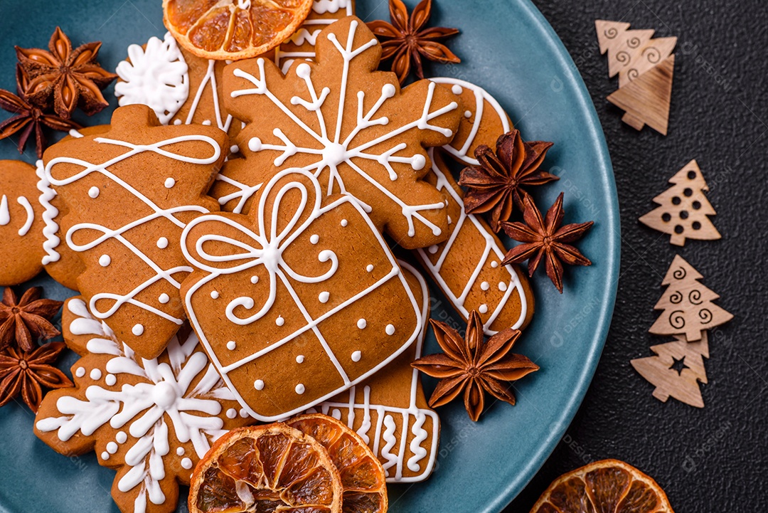 Lindos biscoitos de gengibre de Natal de cores diferentes em uma placa de cerâmica sobre uma mesa de concreto escuro