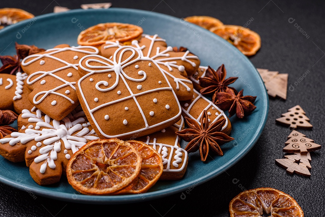 Lindos biscoitos de gengibre de Natal de cores diferentes em uma placa de cerâmica sobre uma mesa de concreto escuro