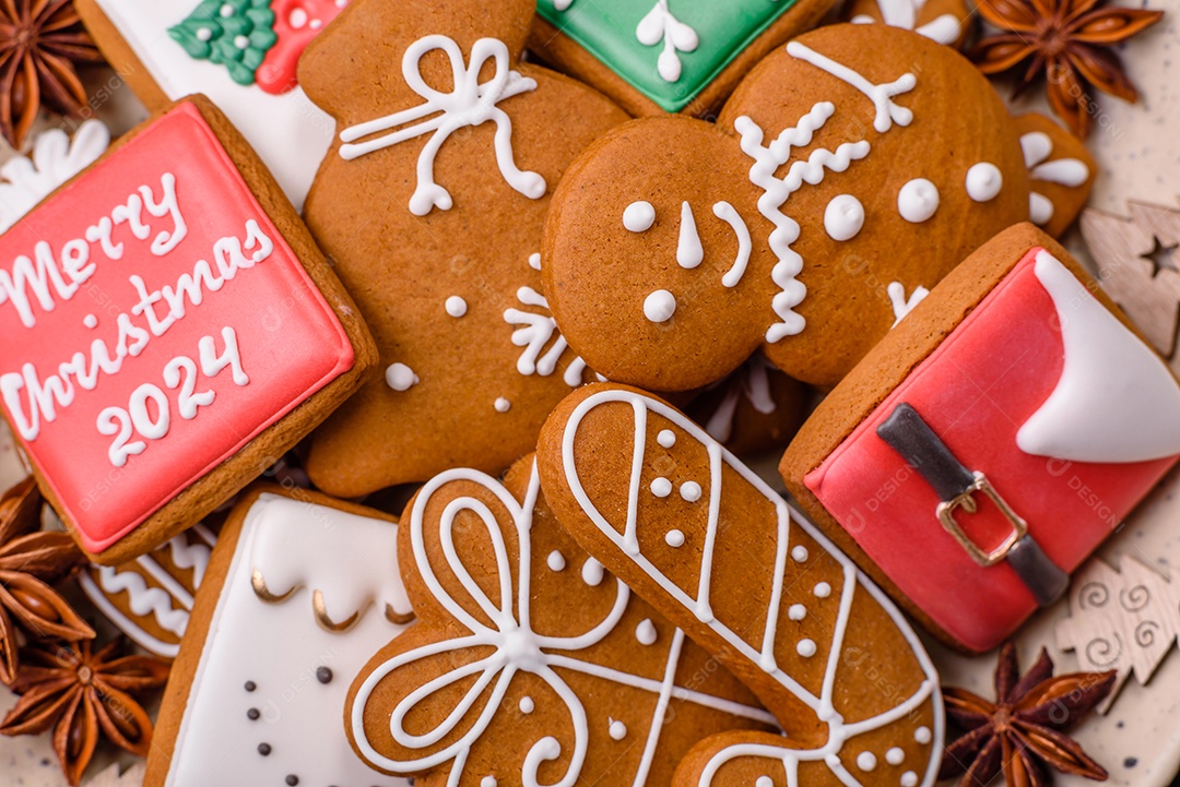 Lindos biscoitos de gengibre de Natal de cores diferentes em uma placa de cerâmica sobre uma mesa de concreto escuro