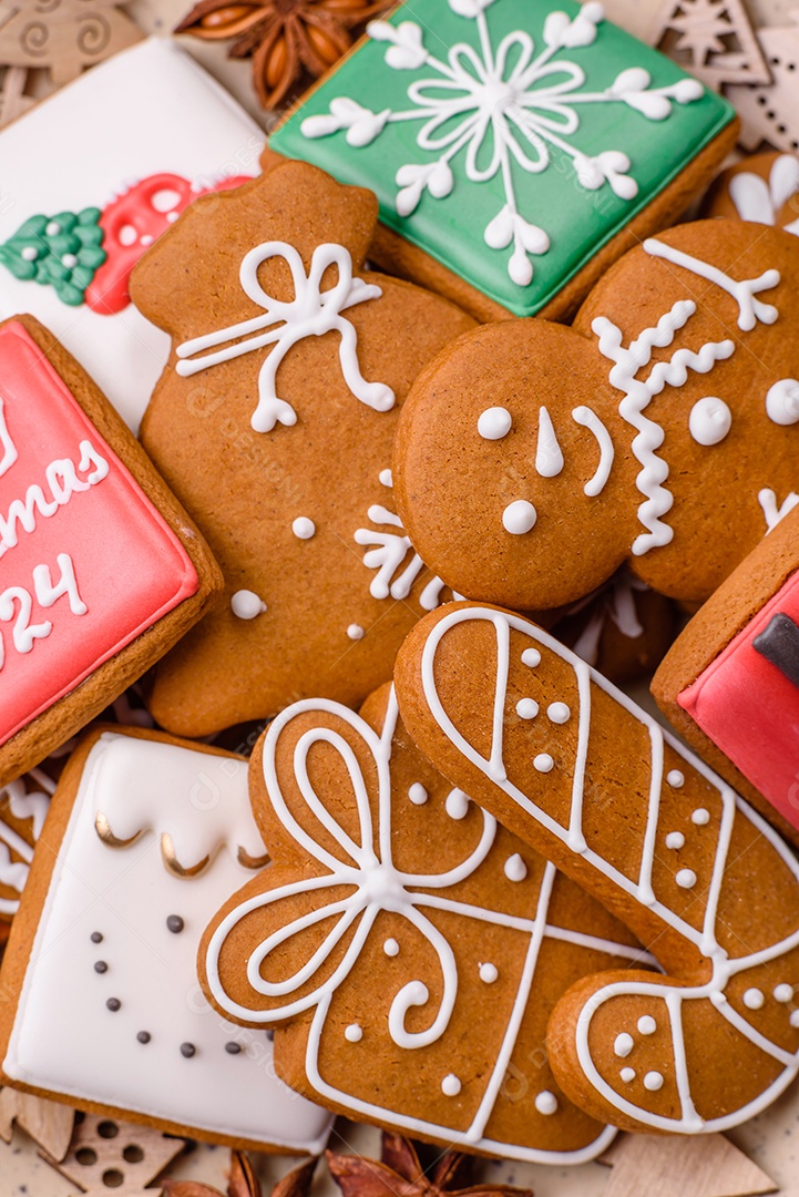 Lindos biscoitos de gengibre de Natal de cores diferentes em uma placa de cerâmica sobre uma mesa de concreto escuro
