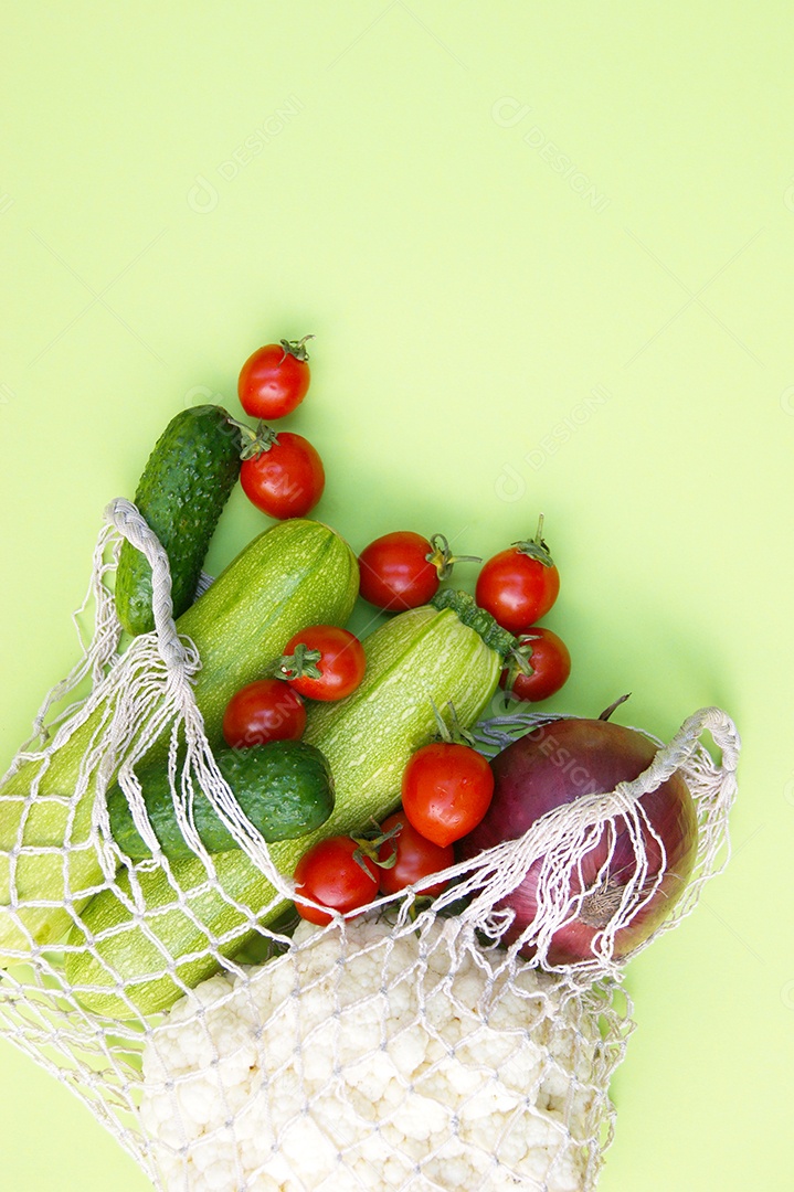 Sacola de barbante cheia de verduras legumes e frutas sobre fundo verde