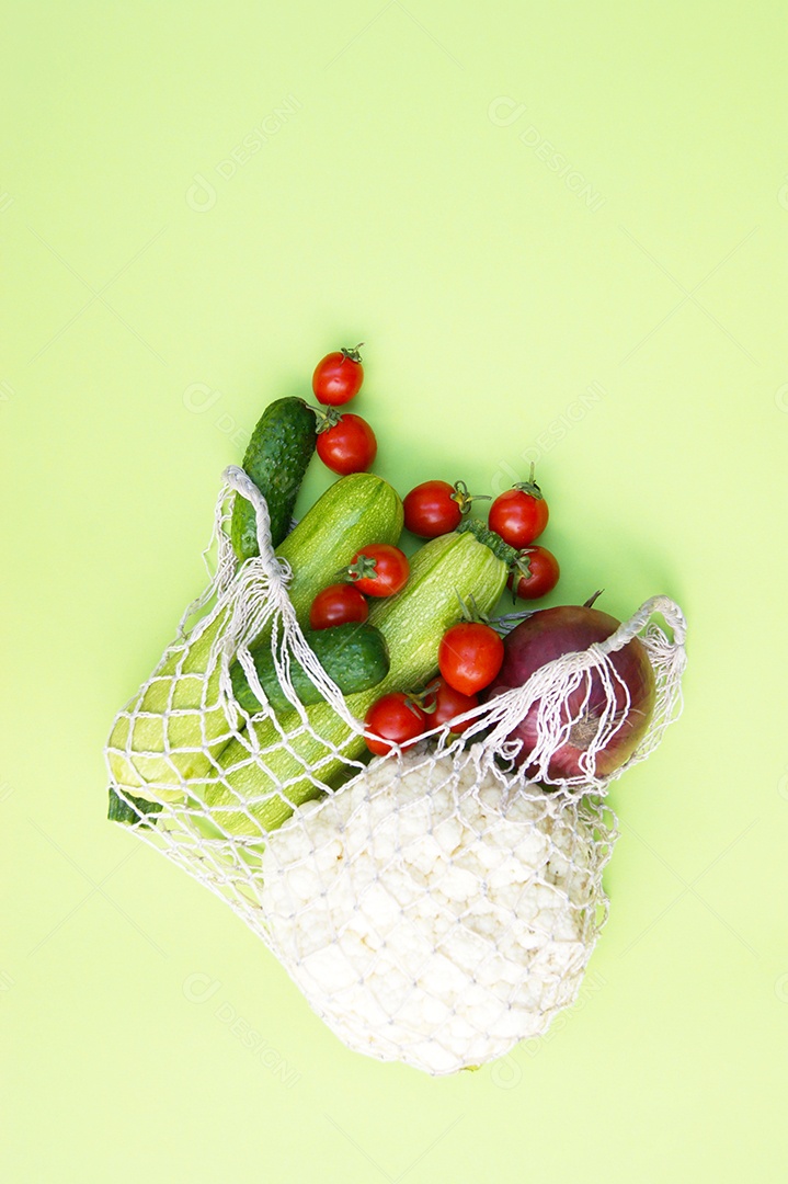 Sacola de barbante cheia de verduras legumes e frutas sobre fundo verde