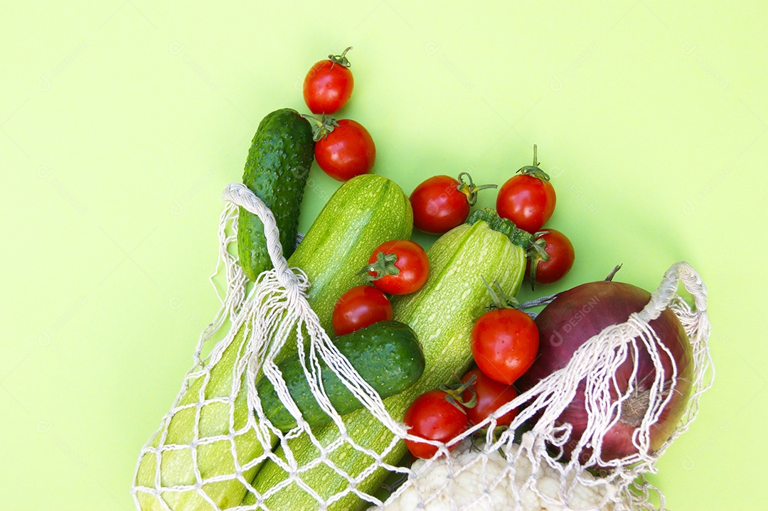 Sacola de barbante cheia de verduras legumes e frutas sobre fundo verde