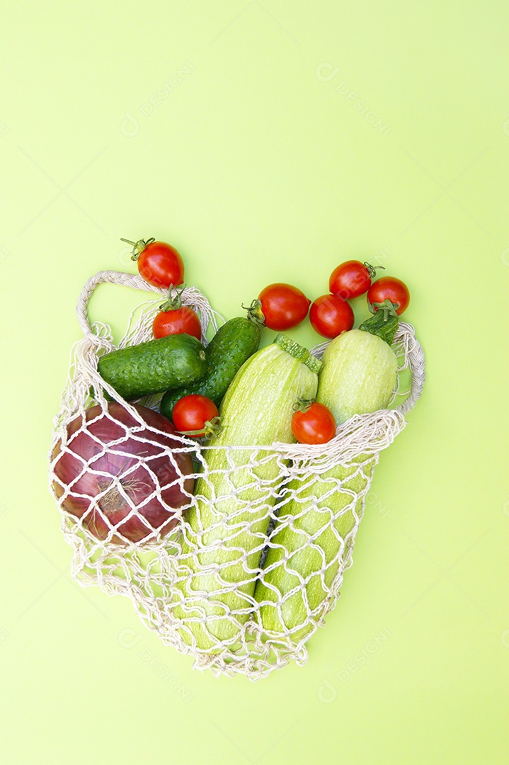Tomates vermelho pepinos verdes e abobrinha em um saco de barbante