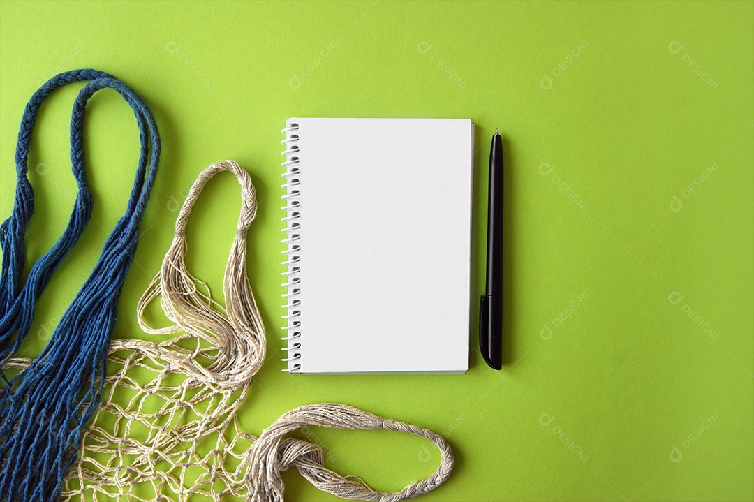 Dois saco de compras reutilizável e caderno com caneta sobre fundo verde