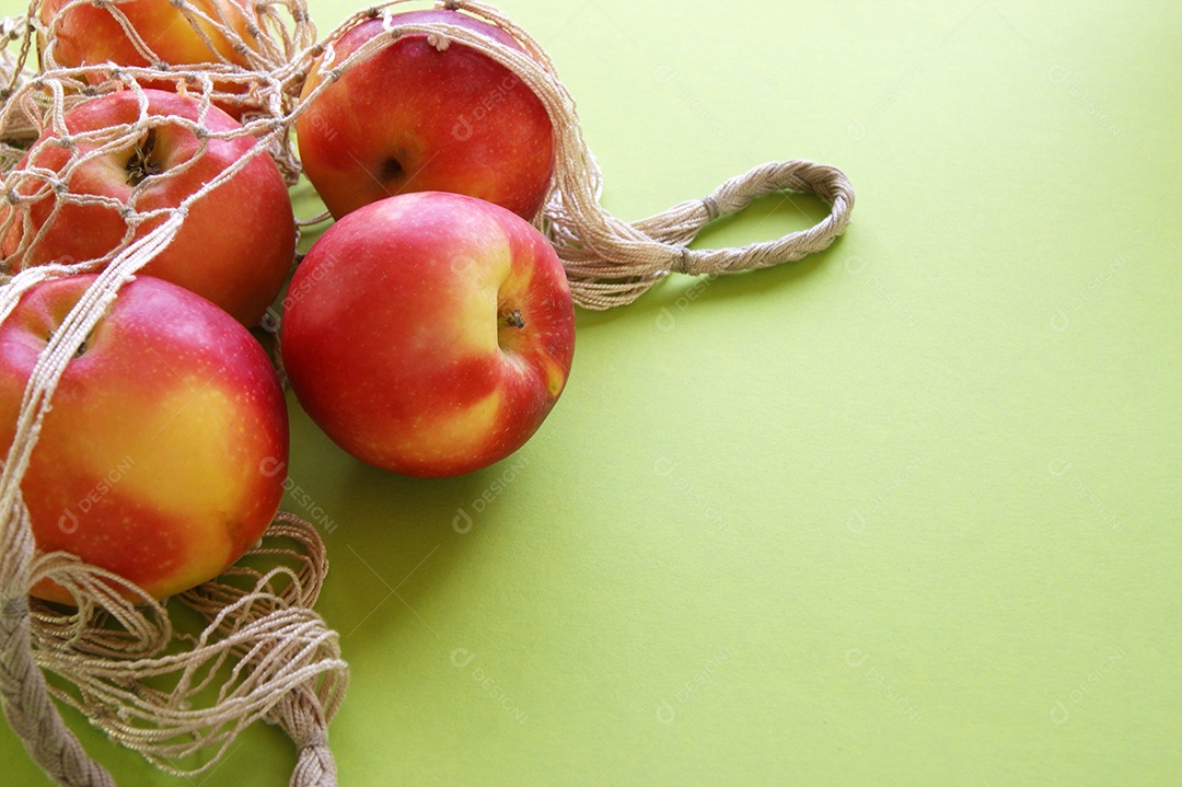 Saco de barbante com maçã sobre fundo verde