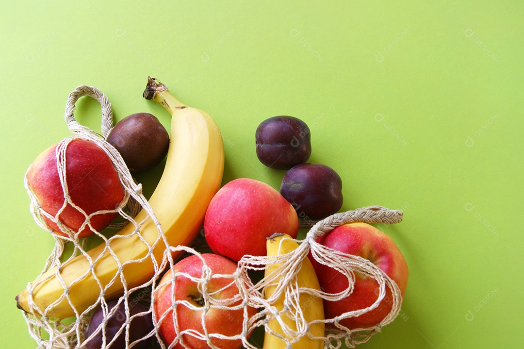 Saco de barbante com frutas sobre fundo verde