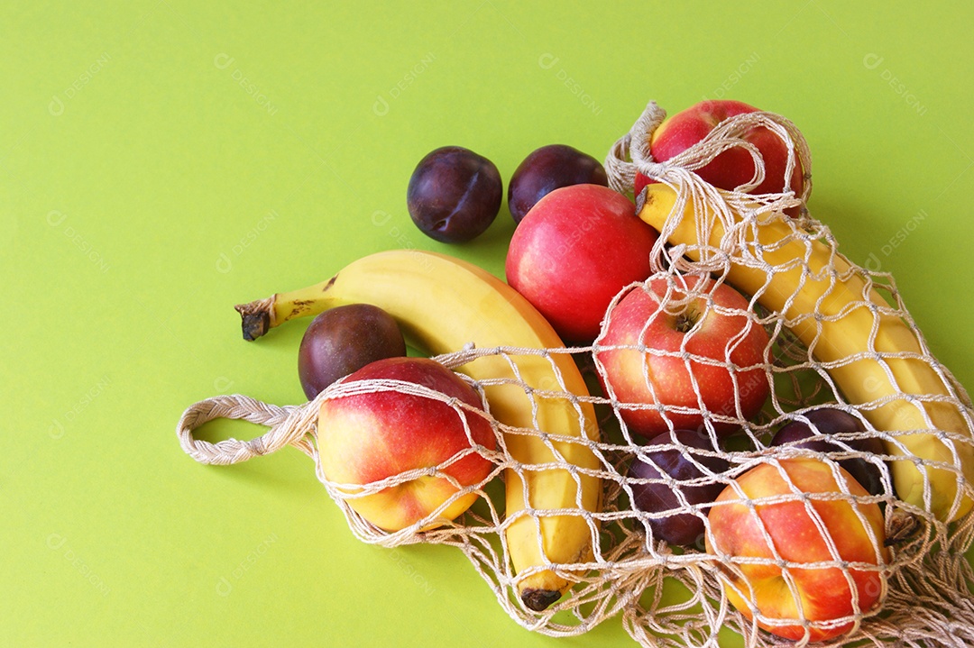 Frutas frescas dentro de saco de barbante sobre fundo verde