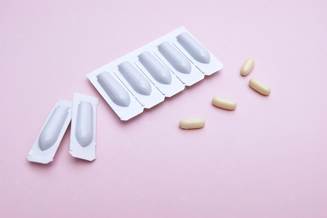 Supositório e comprimidos sobre fundo rosa