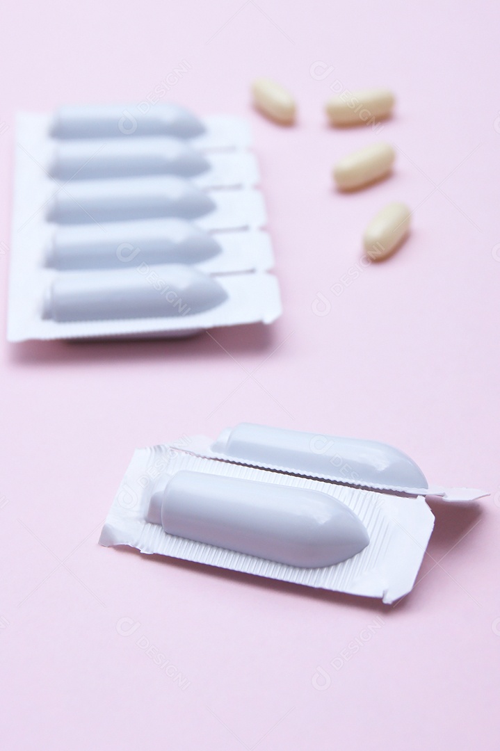 Supositório e comprimidos sobre fundo rosa