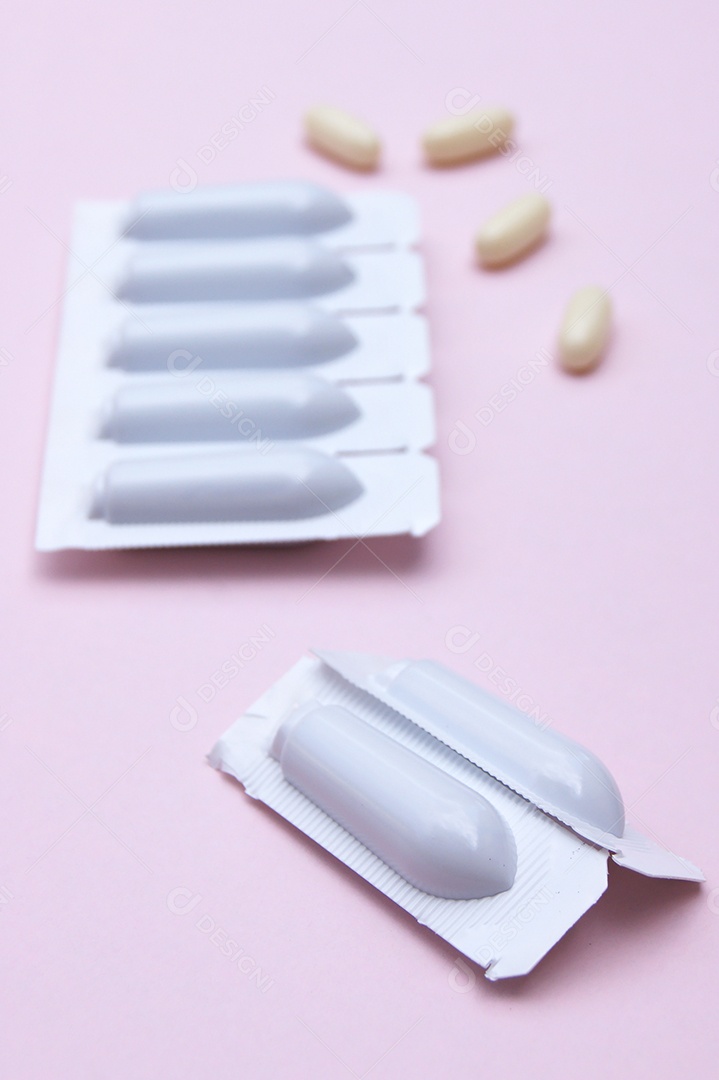 Supositório e comprimidos sobre fundo rosa