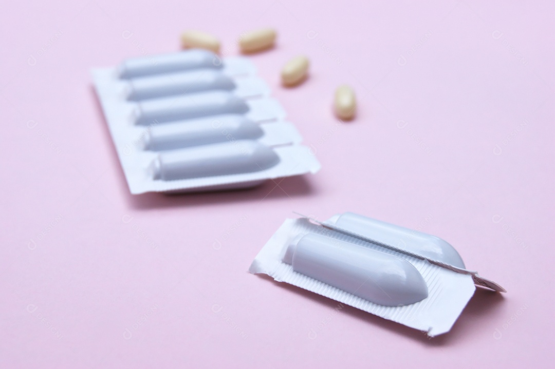 Supositório e comprimidos sobre fundo rosa