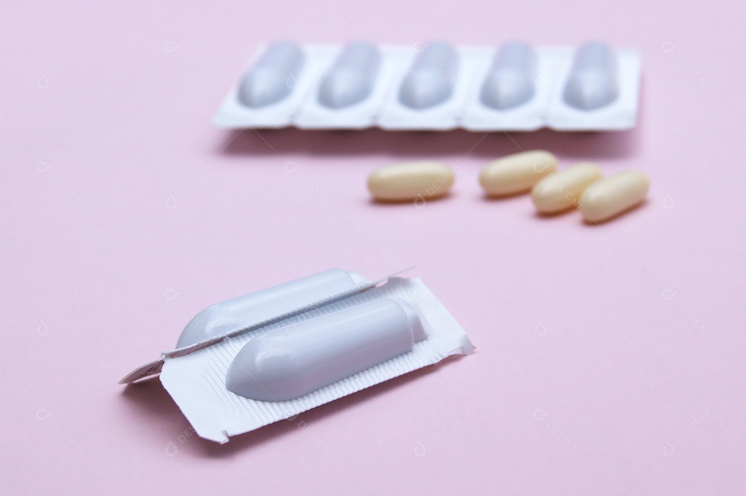 Supositório e comprimidos sobre fundo rosa