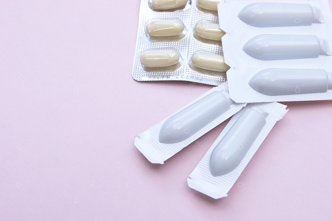 Cartelas de medicamentos e supositório  em um fundo rosa