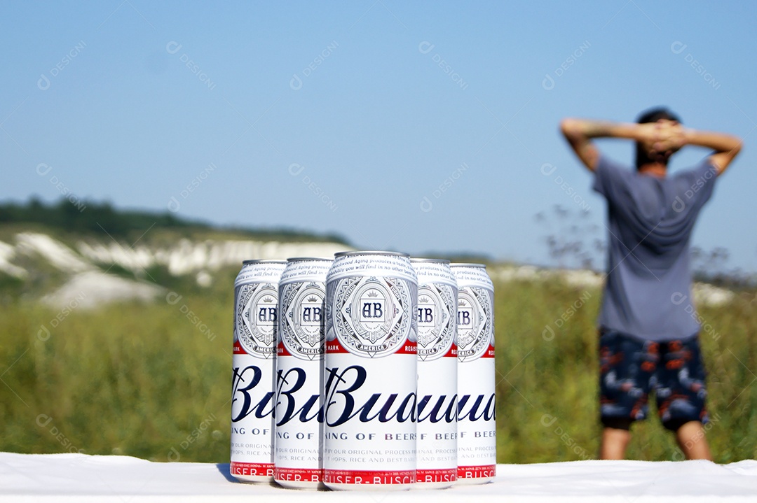 Budweiser em latas sobre um banco e fundo de natureza com um homem se alongando