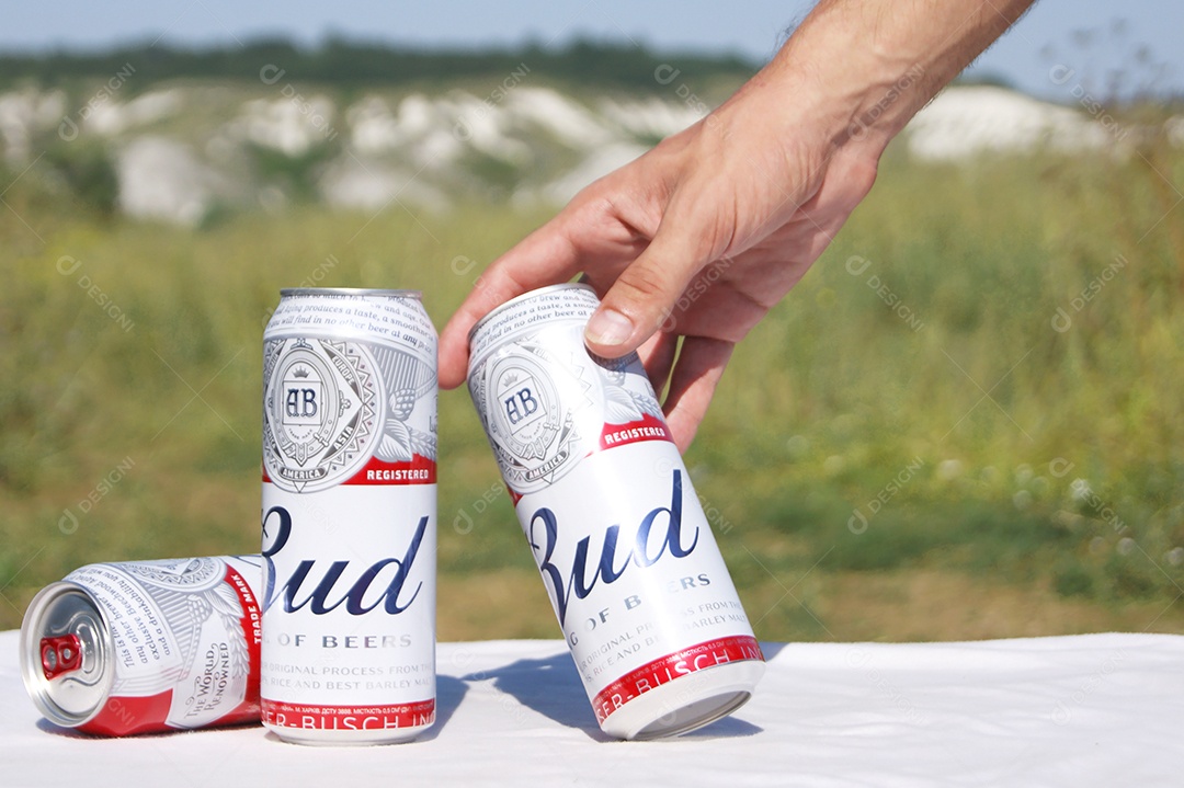 Três latas de Budweiser com fundo de natureza