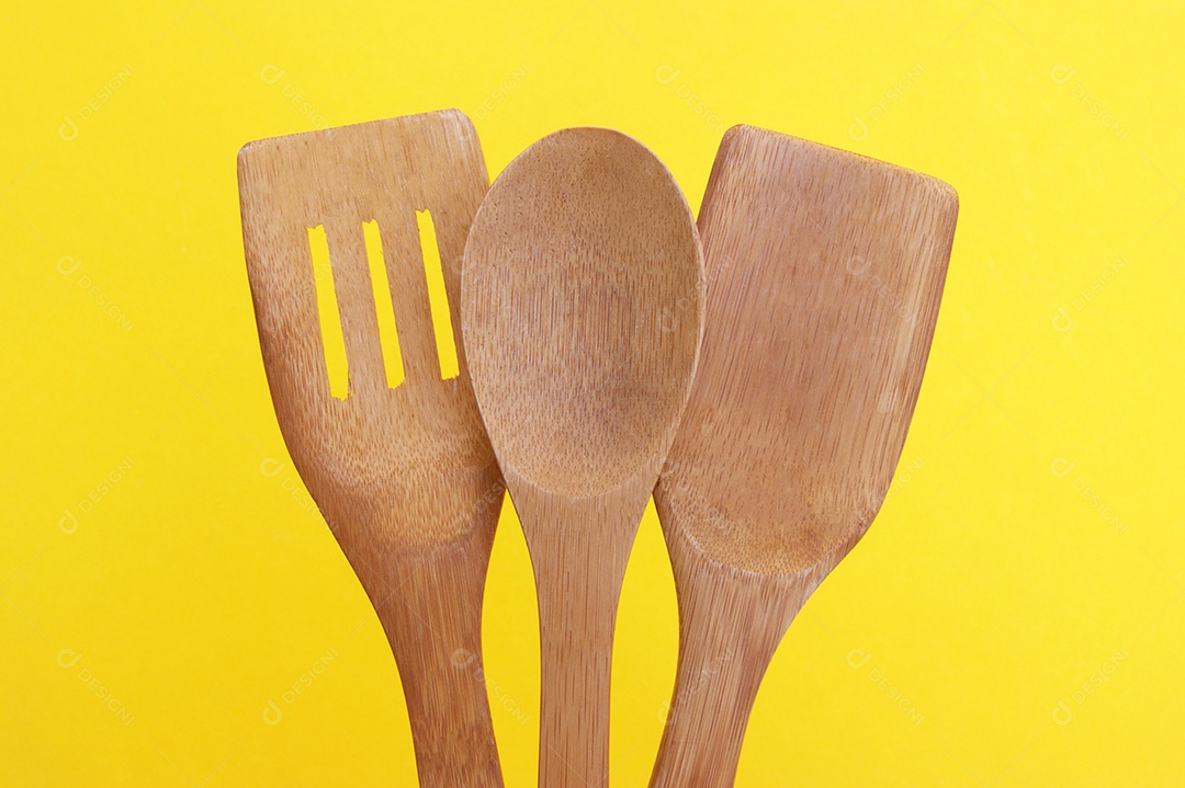 Três colheres de madeira sobre fundo amarelo