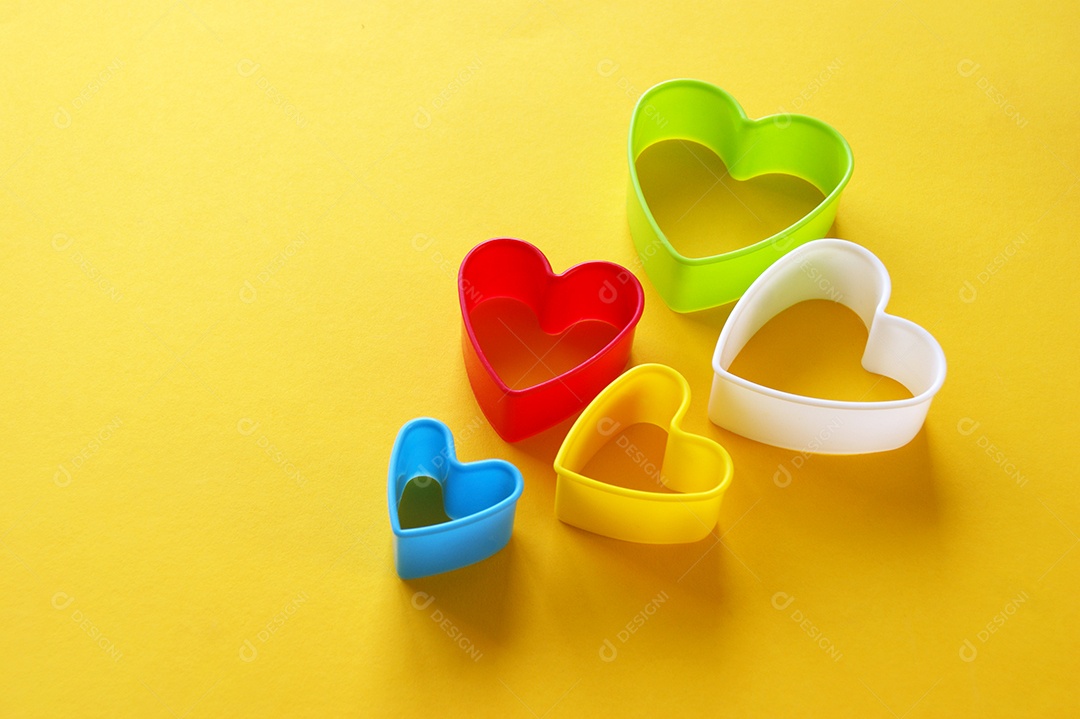 Formas de coração de plástico sobre fundo amarelo