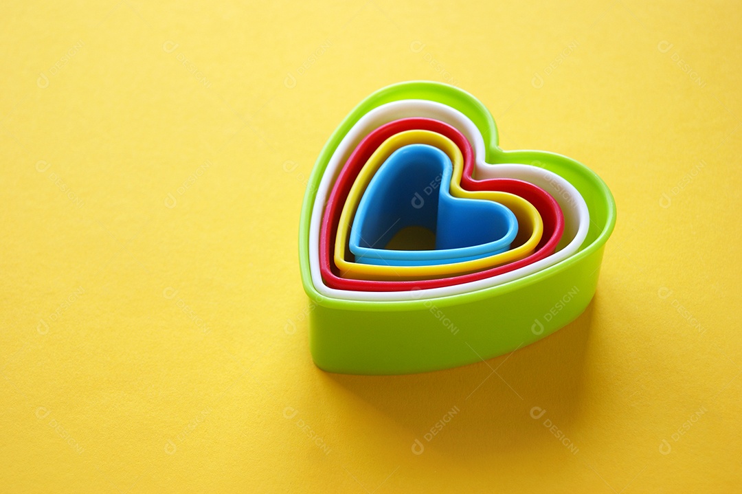 Formas coloridas em formato de coração colorida sobre fundo amarelo