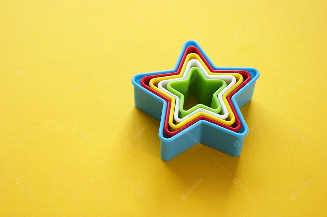 Moldes de plástico multicoloridos em forma de estrela sobre fundo amarelo