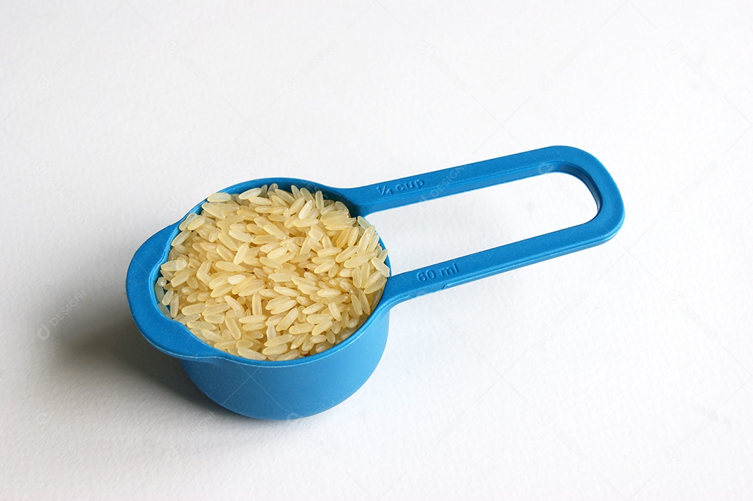 Colher de medida com arroz dentro sobre fundo branco