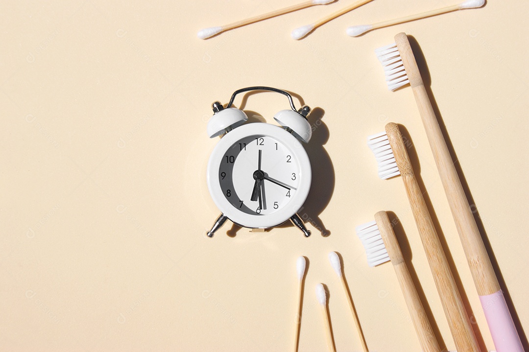 Escovas de dentes de bambu despertador branco e palitos de bambu sobre fundo claro