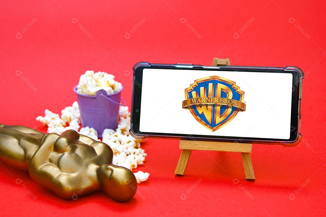 Celular com logotipo Warner Bros pipoca e troféu conceito de premiação cinematográfica
