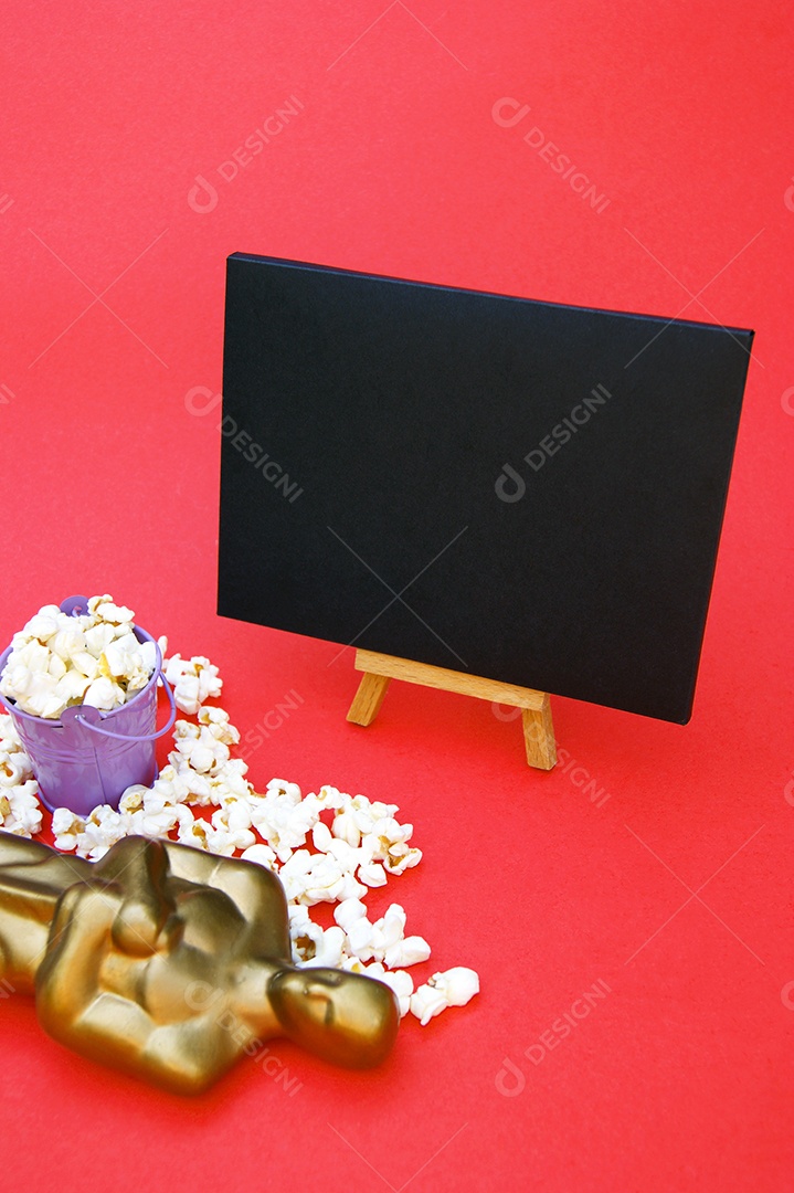 Prêmio Oscar de plástico sobre fundo vermelho com pipoca e envelope preto