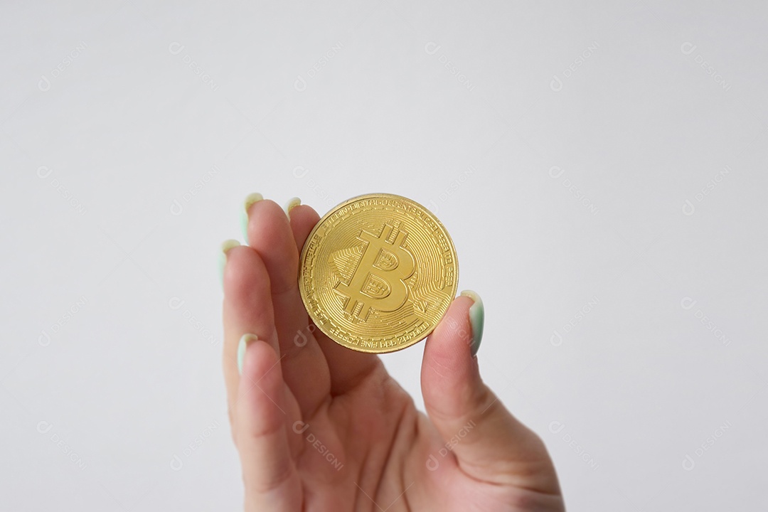 Mão segurando uma moeda de Bitcoin